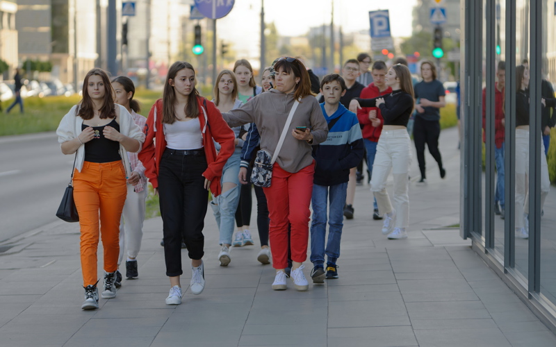 15 - A diverse group of people walking together along a paved city sidewalk outdoors